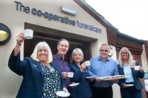Woodville Co-op funeral arranger raising cup at coffee morning with other VIPs